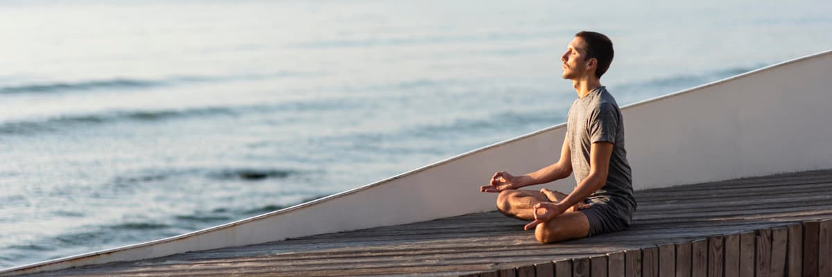 Man doing sukhasana pose outside