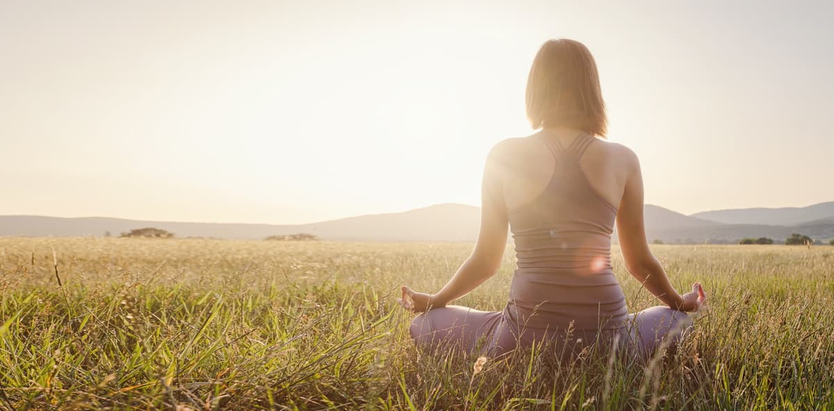 Woman practices yoga in lotus position in a field